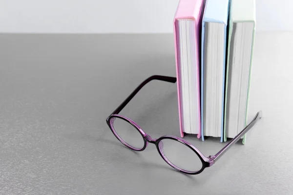 Böcker och glasögon på grå bord — Stockfoto