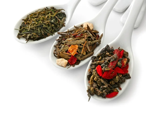 Различные виды сухого чая в керамических ложках, изолированные на белом — стоковое фото