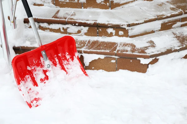 Red shovel for snow removal beside stairs — Stock Photo, Image