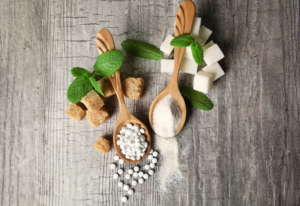 Montón de terrones de azúcar moreno y stevia sobre fondo de madera gris — Foto de Stock