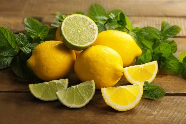 Limoni freschi affettati e lime con foglie verdi — Foto Stock