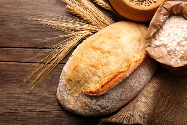 Fresh baked bread, flour and wheat on the wooden background — Stock Photo, Image