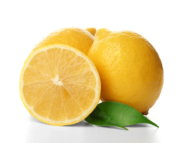Свежие лимоны с половинками и зелеными листьями — стоковое фото