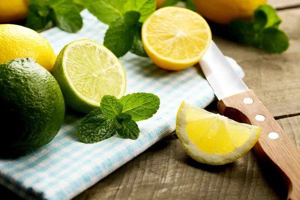 Sliced fresh lemon and lime with green leaves on blue napkin closeup — Stock Photo, Image