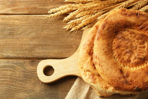 Düz ekmek ve buğday kulaklara bir ahşap kesme tahtası, üstten görünüm