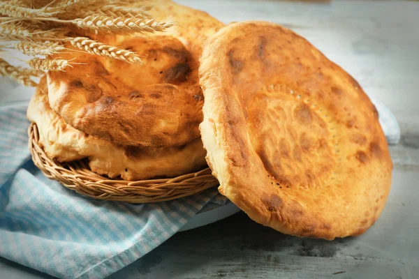 Flat bread and wheat ears on napkin on wooden background — Stock Photo, Image