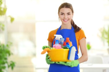 Woman in gloves holding basin with detergents 