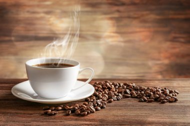 Cup of coffee with grains on wooden background clipart