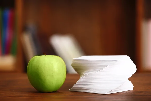 Manzana y papel sobre la mesa en la habitación —  Fotos de Stock