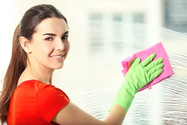 Young woman washing window glass indoors — Stock Photo, Image