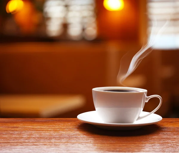 Φλιτζάνι καφέ στο τραπέζι σε καφέ φόντο blured — Φωτογραφία Αρχείου