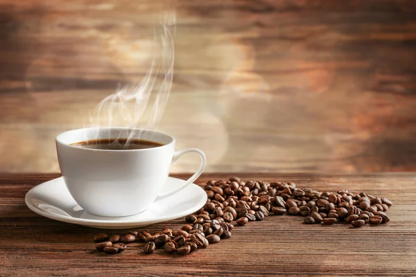 Tasse de café avec des grains sur fond en bois — Photo