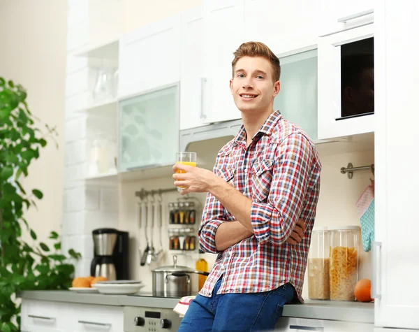 Handsome man with juice in kitchen