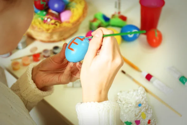 Женские руки рисуют пасхальные яйца — стоковое фото