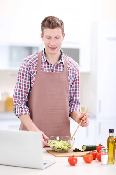 Hombre cocina ensalada de verduras en la cocina —  Fotos de Stock