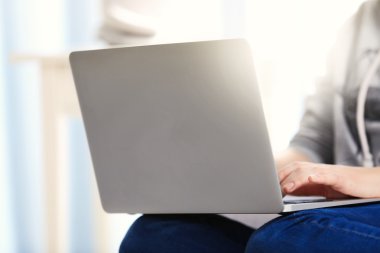 Kanepede dizüstü bilgisayarlı bir kadın oturuyor. 