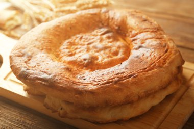 Düz ekmek ve buğday kulaklara bir ahşap kesme tahtası