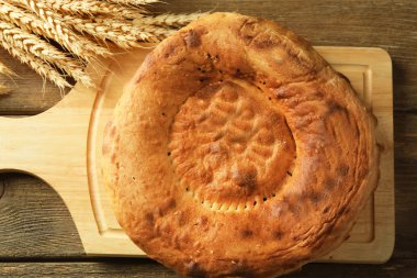 Düz ekmek ve buğday kulaklara bir ahşap kesme tahtası, üstten görünüm
