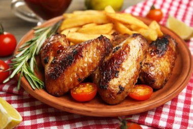 Fırında tavuk kanadı ile kızarmış patates kahverengi plaka üzerinde