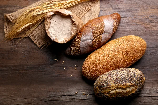 Fresh baked bread, flour and wheat on the wooden background — Stock Photo, Image