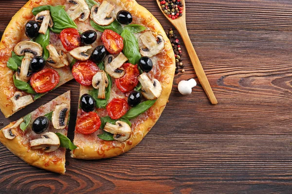 Szeletelt finom ízletes pizza zöldségekkel, a fából készült asztal — Stock Fotó