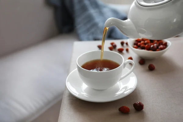 Versare il tè rosa canina in tazza, atmosfera domestica — Foto Stock