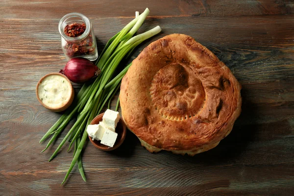 Свежий жареный хлеб с сыром, блюдцем и весенним луком на деревянном фоне — стоковое фото