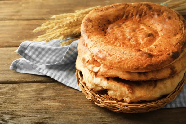 Flat bread and wheat ears on napkin on wooden background — Stock Photo, Image