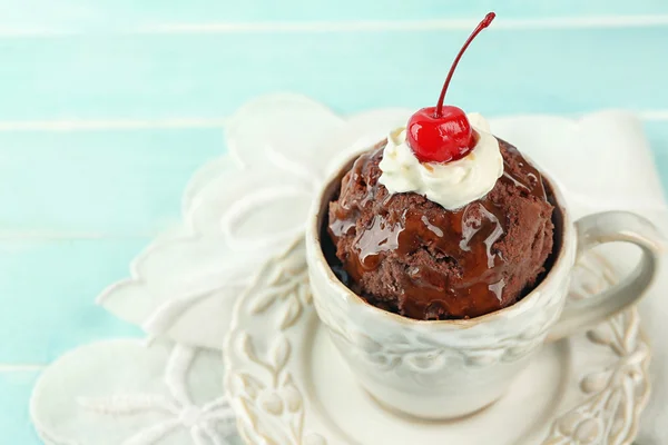 Ciasto czekoladowe kubek z cream i cherry na niebieskim tle drewniane — Zdjęcie stockowe