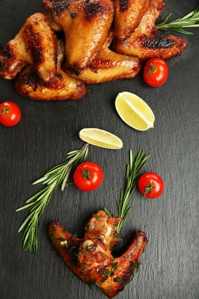 Baked chicken wings with tomatoes and rosemary on slate plate — Stock Photo, Image