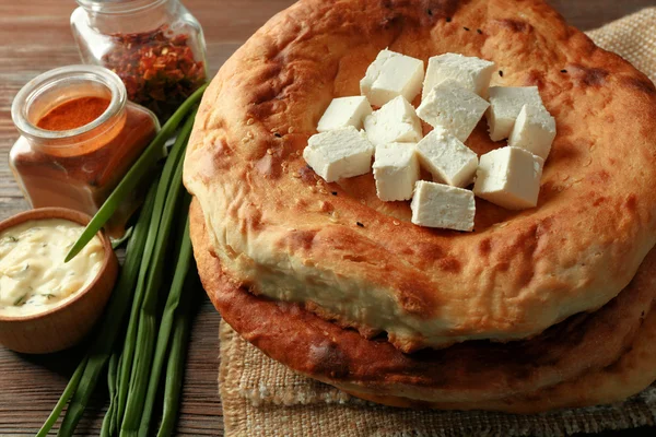 Fresh fried bread with saucer, spices and cubes of cheese on wooden table closeup — Stock Photo, Image