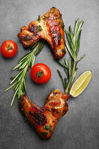 Baked chicken wings with tomatoes and rosemary on grey background — Stock Photo, Image