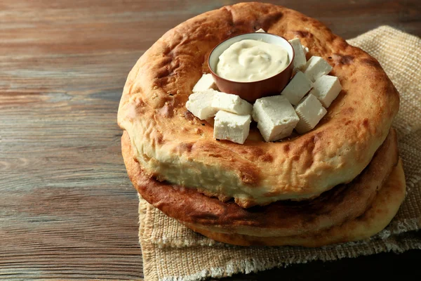 Fresh fried bread with sauce and cubes of cheese on wooden background — Stock Photo, Image