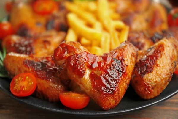 Grillad kyckling vingar med pommes frites, tomater på plattan och trädgård-personal — Stockfoto