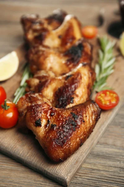 Asas de frango assadas com tomates e alecrim na tábua de corte — Fotografia de Stock