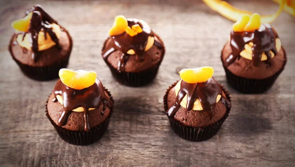 Tasty cupcakes with slice of mandarin and chocolate on wooden background — Stock Photo, Image