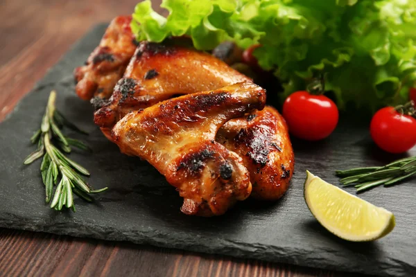 Baked chicken wings with vegetables on slate plate — Stock Photo, Image