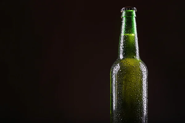 Frasco de vidro verde de cerveja no fundo escuro, de perto — Fotografia de Stock