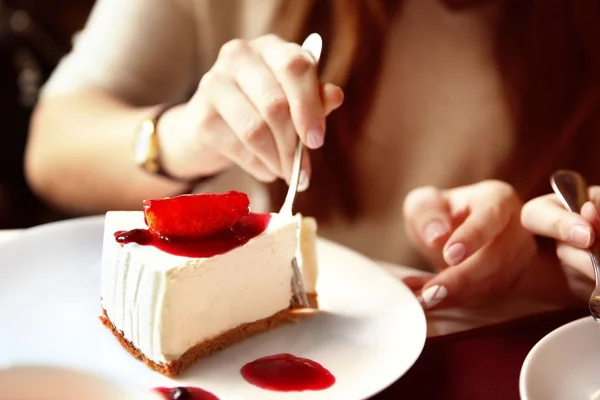 Donna che mangia gustosa torta di formaggio sul tavolo in caffè o ristorante — Foto Stock