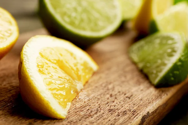 Sliced fresh lemon and lime on wooden cutting board closeup — Stock Photo, Image