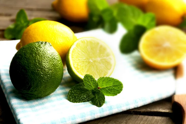 Limone fresco affettato e lime con foglie verdi sul primo piano del tovagliolo blu — Foto Stock