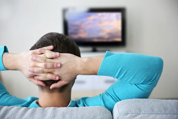 Young man watching TV at home