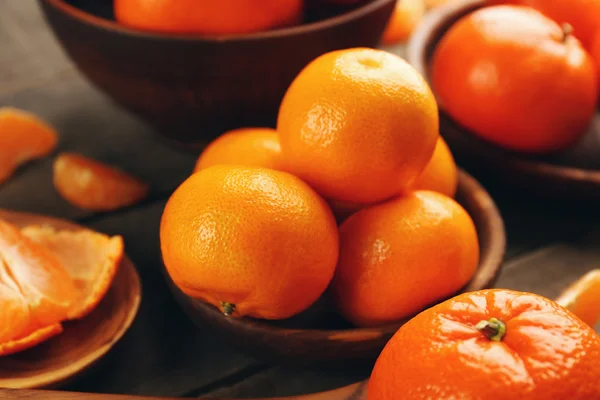 Mandarines pelées et non pelées dans des cuillères et des bols en bois, fermer — Photo