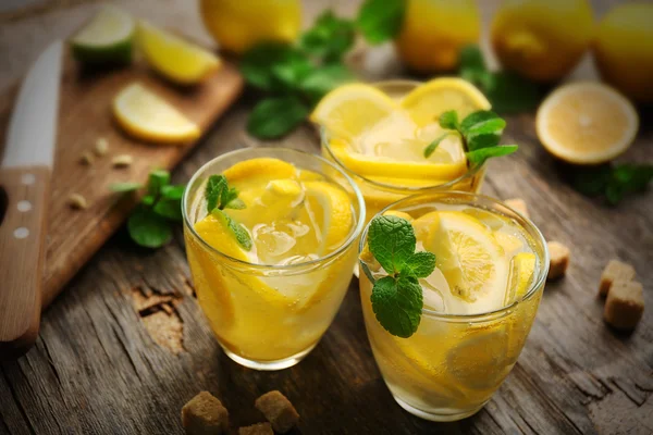 Composição limonadas com limões e hortelã sobre fundo mesa de madeira — Fotografia de Stock