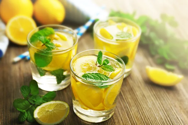 Composición de limonadas, limones y menta sobre fondo de mesa de madera, primer plano — Foto de Stock