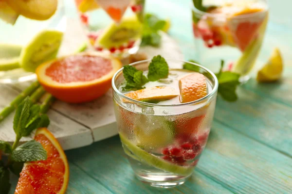 Verfrissende cocktail met ijs, munt, granaatappel zaden en segmenten van vruchten op blauwe houten achtergrond — Stockfoto