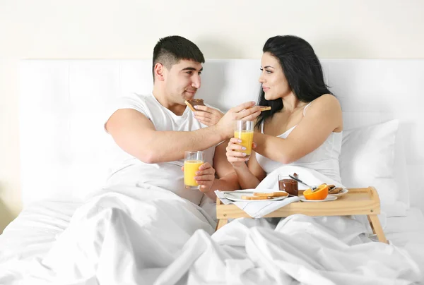 ベッドで朝食を持っている素敵なカップル — ストック写真