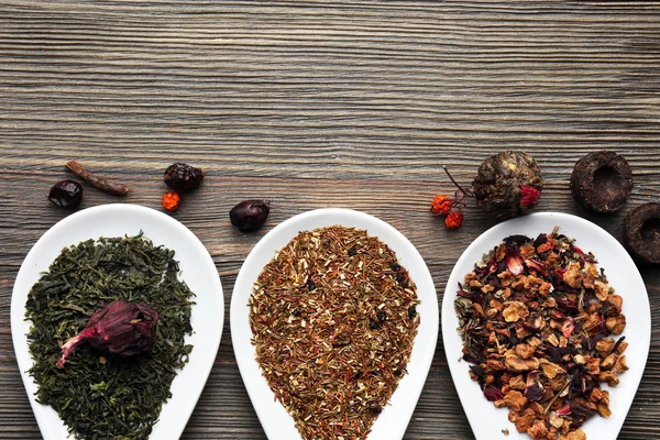 Tea concept. Different kinds of tea in ceramic bowls on wooden background — Stock Photo, Image