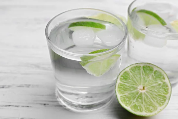 Cocktails frais avec glace et citron vert sur fond de table en bois blanc — Photo