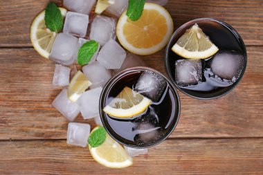 İki bardak kola ile küpleri buz ve limon ahşap masa arka plan üzerinde
